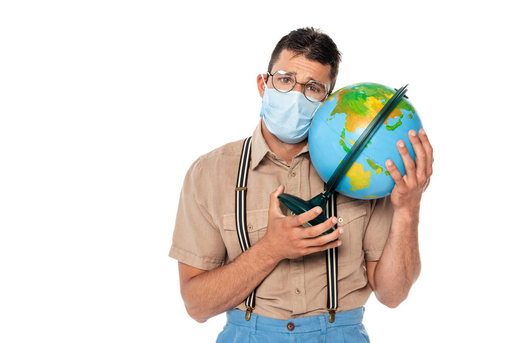 Triste nerd dans le masque médical tenant globe isolé sur blanc - Photo, image