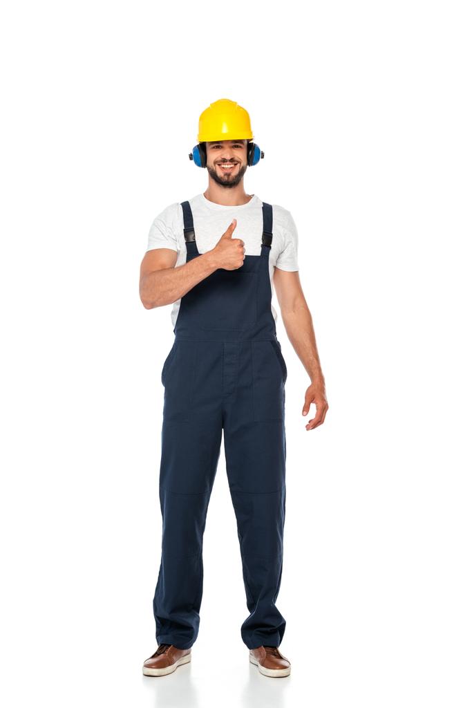 Komea rakentaja työvaatteissa ja kypärä hymyilee ja näyttää peukalo ylös ele valkoisella taustalla - Valokuva, kuva
