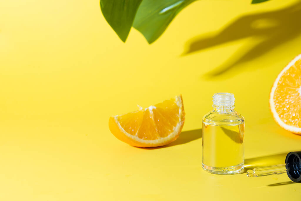 Cosmetic hyaluronic acid or hydrating oil and orange essence on yellow background. Anti-cellulit care. Space for text. - Photo, Image