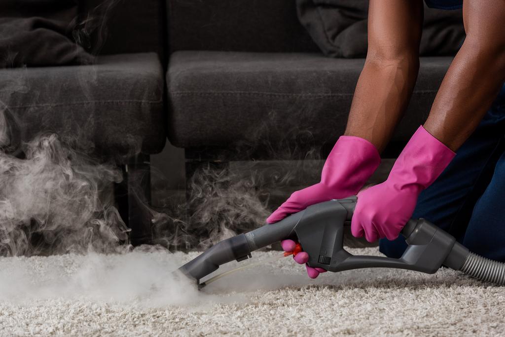 Oříznutý pohled na africký americký čistící koberec s horkou párou  - Fotografie, Obrázek