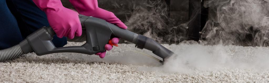 Панорамний урожай прибиральника в гумових рукавичках з використанням пилососа з гарячою парою на килимі
  - Фото, зображення