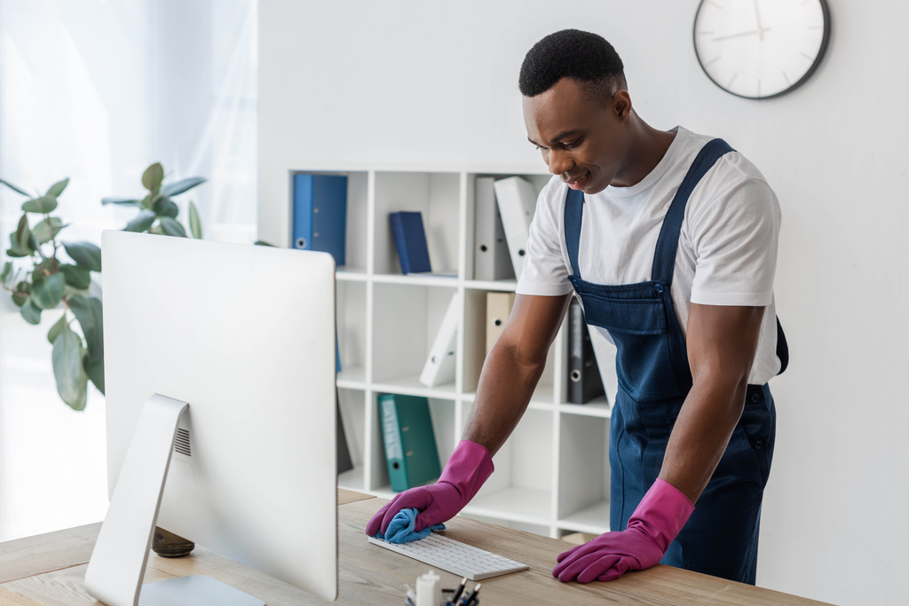 Travailleur afro-américain de nettoyage service nettoyage clavier d'ordinateur avec chiffon dans le bureau  - Photo, image