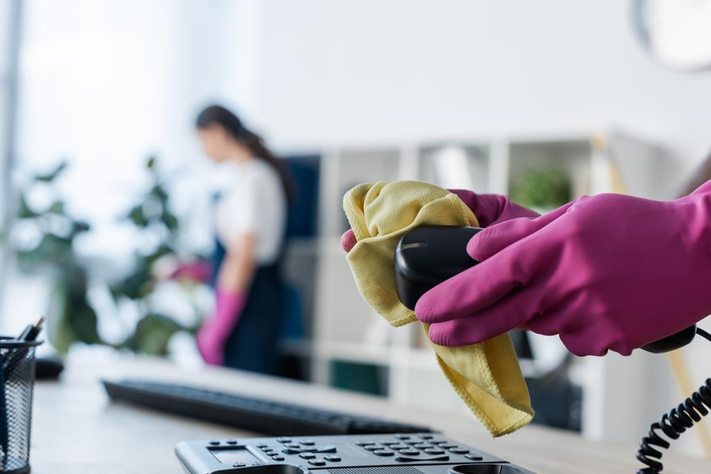 Enfoque selectivo del limpiador en guantes de goma teléfono de limpieza cerca de colega en la oficina
  - Foto, Imagen