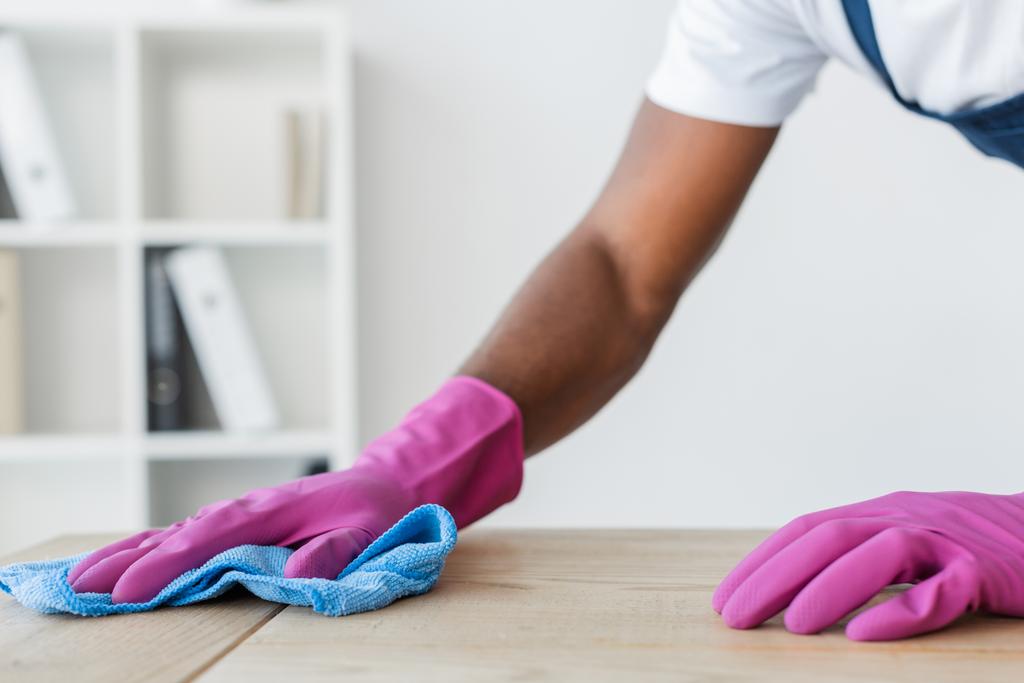 Vista recortada de trabajador afroamericano de servicio de limpieza mesa de oficina de limpieza
  - Foto, Imagen