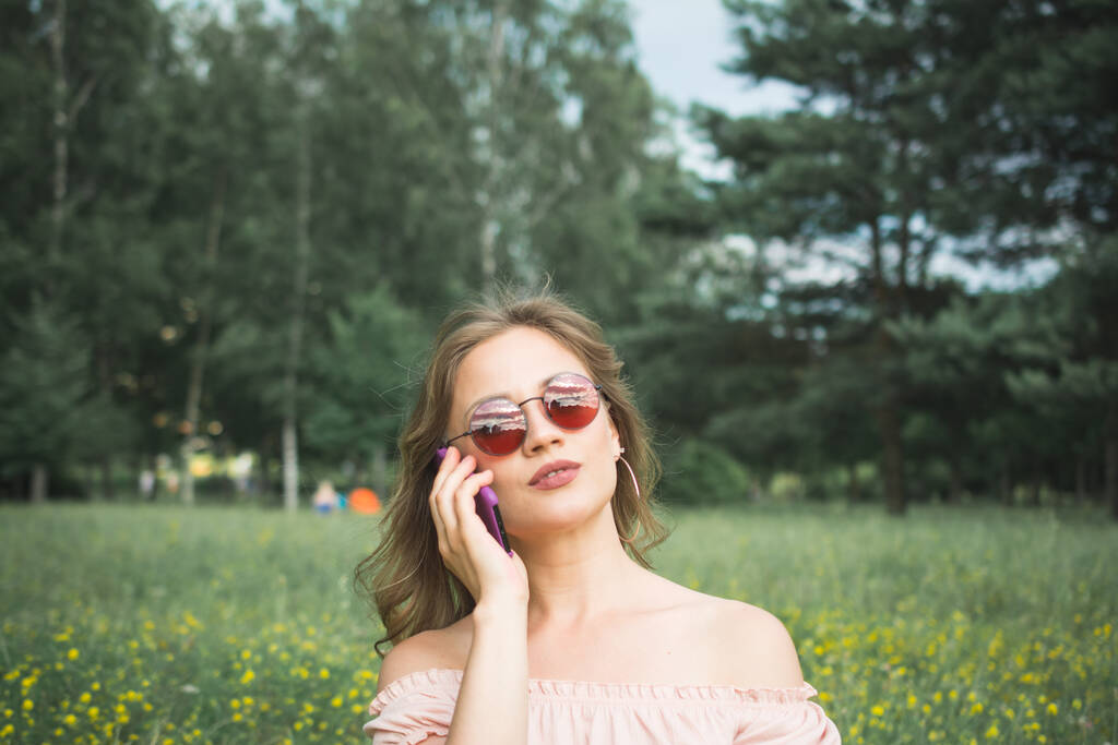 ritratto di una giovane ragazza alla moda che parla al telefono nel parco - Foto, immagini