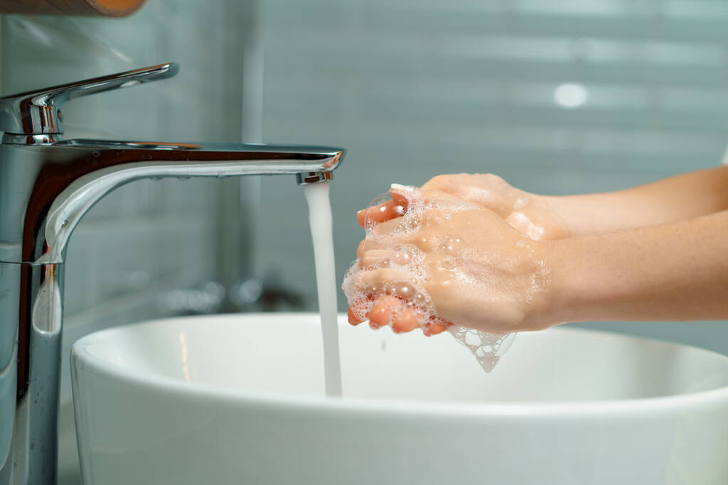 Nahaufnahme einer Frau, die sich in einem Waschbecken im Badezimmer die Hände wäscht - Foto, Bild
