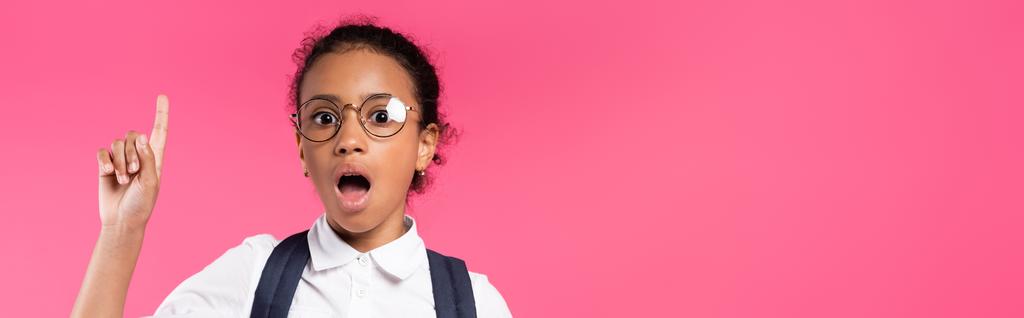 shocked african american schoolgirl in glasses showing idea gesture isolated on pink, panoramic shot - Photo, Image