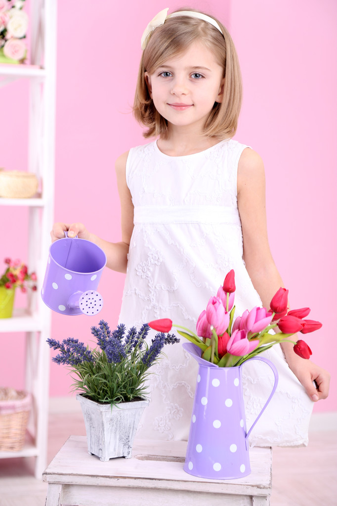Hermosa niña y de pie con flores sobre fondo rosa
 - Foto, imagen