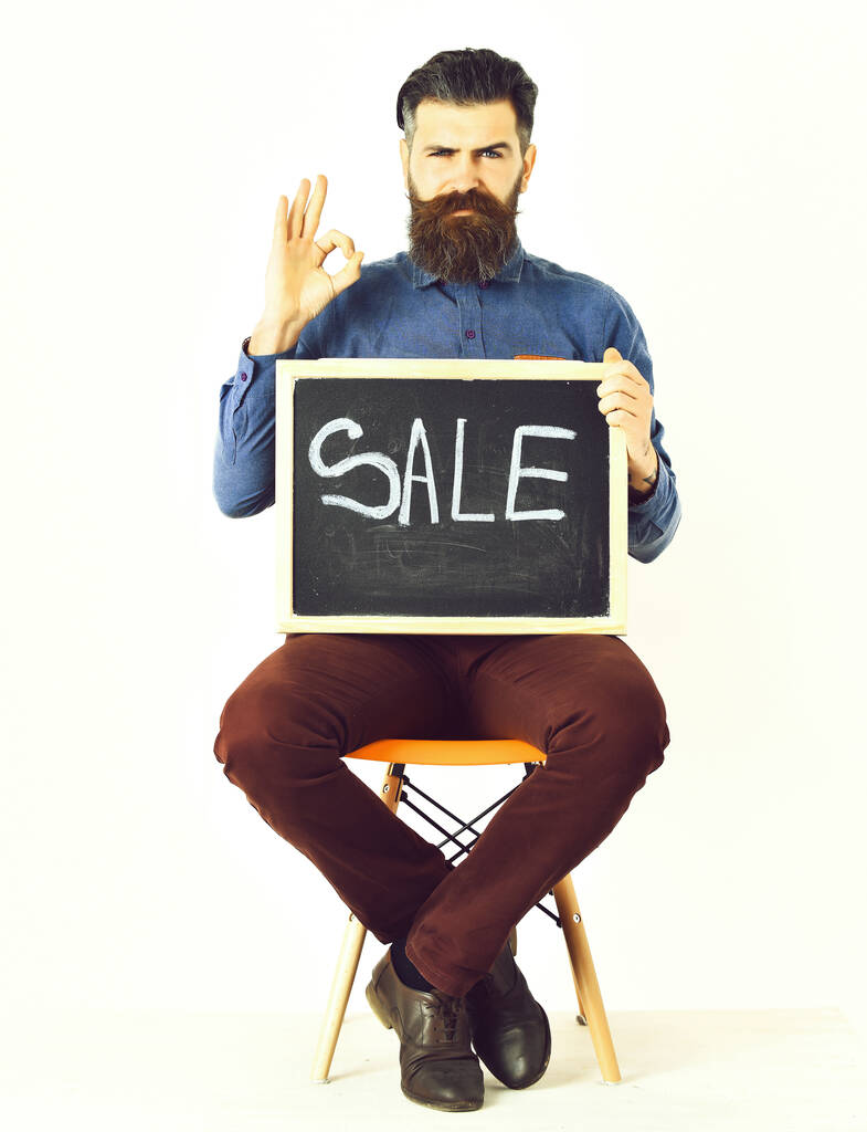 Γενειοφόρος άνδρας, βάρβαρος καυκάσιος χίπστερ με μουστάκι που κρατά την επιγραφή πώλησης - Φωτογραφία, εικόνα