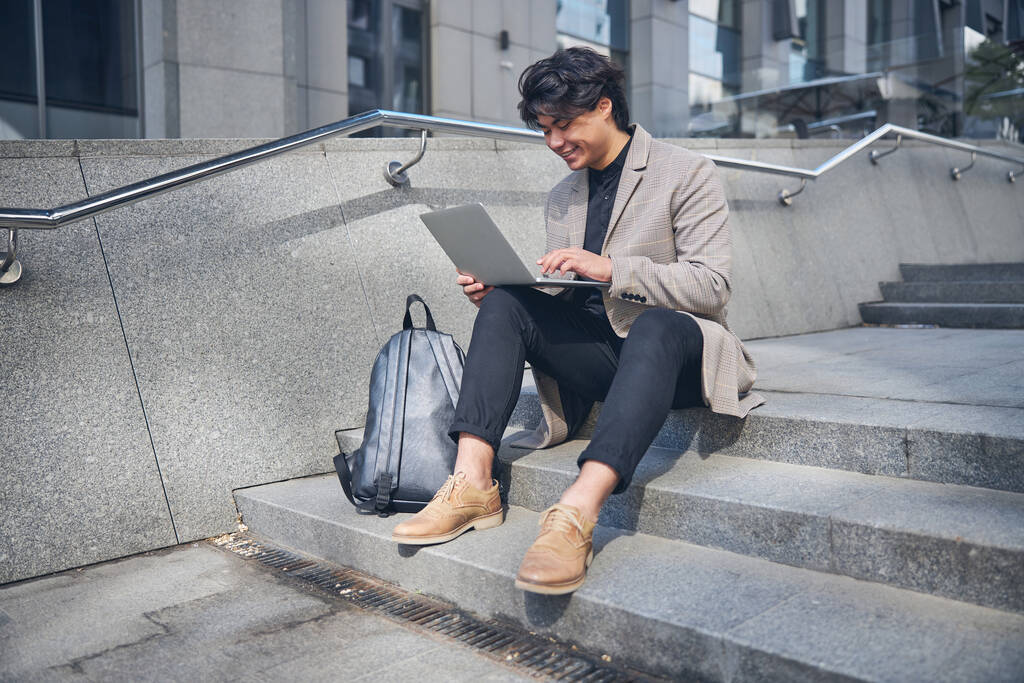 Стильный молодой человек с ноутбуком на улице
 - Фото, изображение