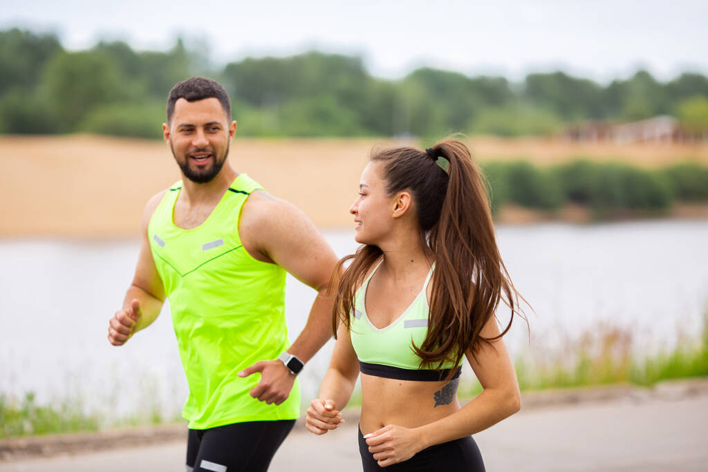 Спортивная счастливая девушка и мужчина в стильной спортивной одежде бегают на природе, фото для блога и рекламы спорта и здорового образа жизни
 - Фото, изображение
