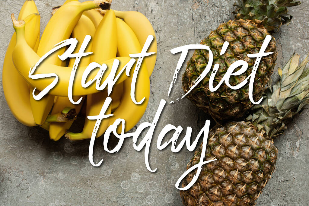 widok z góry kolorowe pyszne banany i ananasy na szarej powierzchni betonu, rozpocząć dietę dziś ilustracja - Zdjęcie, obraz