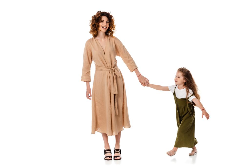 encaracolado mãe e bonito filha segurando as mãos isoladas no branco
  - Foto, Imagem