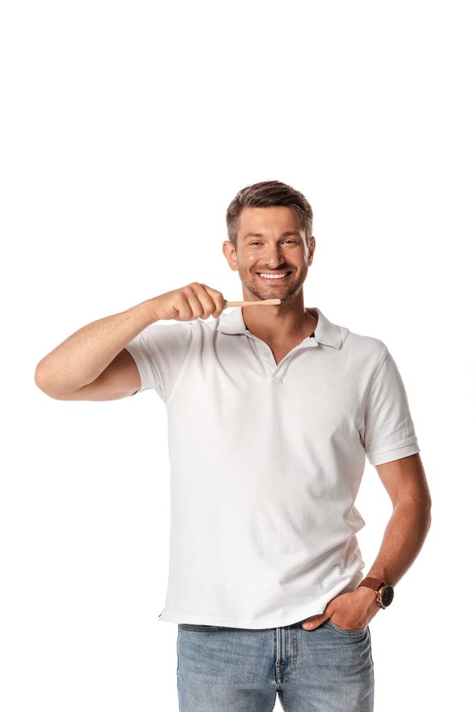 hombre feliz sosteniendo el cepillo de dientes y de pie con la mano en el bolsillo aislado en blanco
  - Foto, imagen
