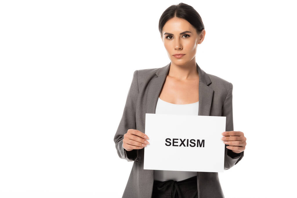 attraente donna d'affari in possesso di cartello con sessismo lettering isolato su bianco - Foto, immagini