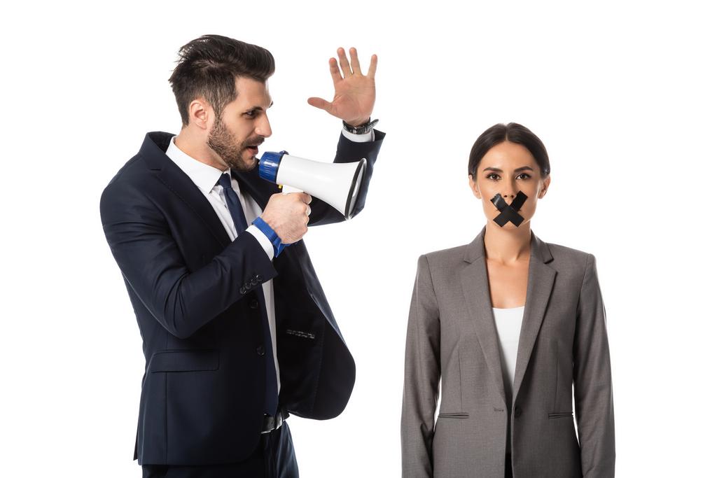 Geschäftsmann schreit in Megafon und gestikuliert in der Nähe Geschäftsfrau mit Klebeband auf Mund isoliert auf weiß - Foto, Bild