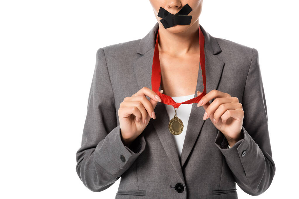 vue recadrée de femme d'affaires avec ruban scotch sur la bouche ruban tactile avec médaille isolé sur blanc  - Photo, image
