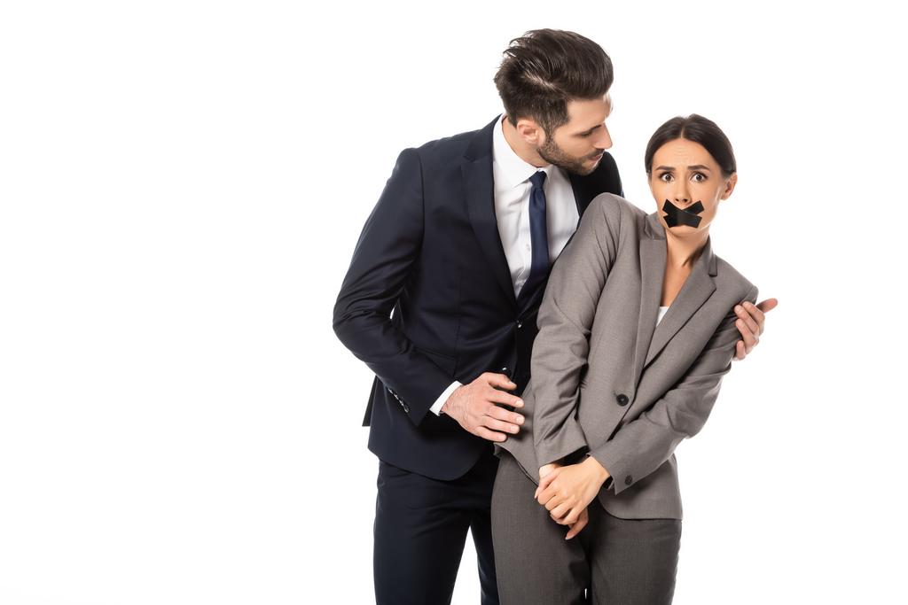 бизнесмен в формальной одежде трогает деловую женщину с скотчем на рту, изолированным на белом, сексуальное домогательство
   - Фото, изображение