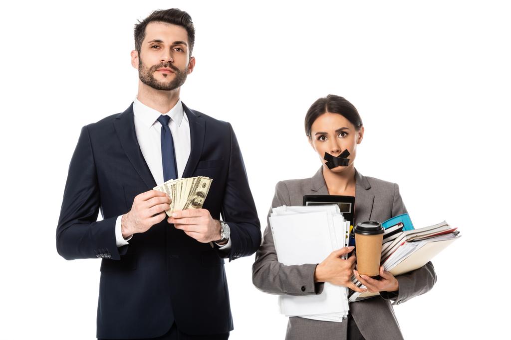 beau homme d'affaires tenant des dollars près d'une femme d'affaires avec du ruban adhésif sur la bouche isolé sur blanc, concept de sexisme  - Photo, image