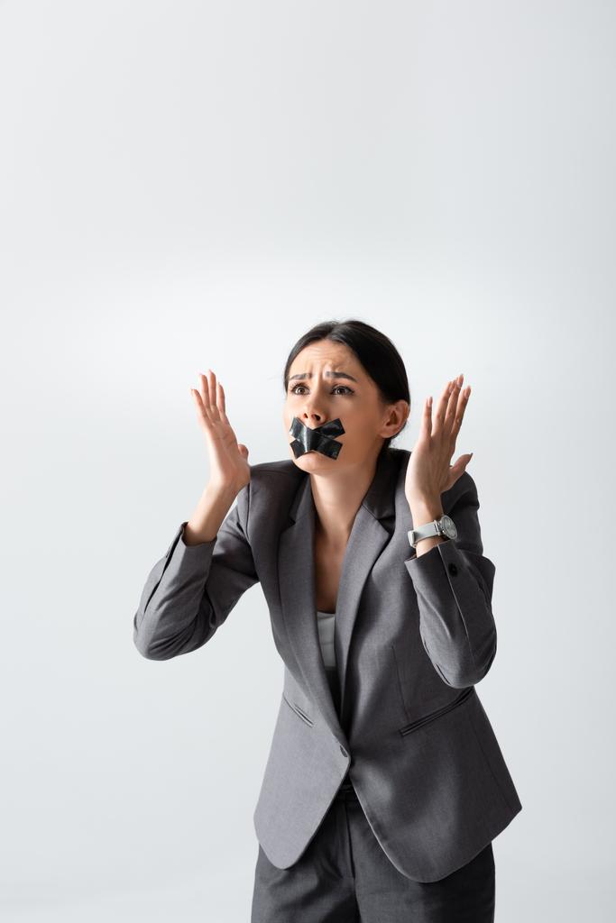 emotionale Geschäftsfrau mit Klebeband auf dem Mund gestikuliert isoliert auf weiß - Foto, Bild