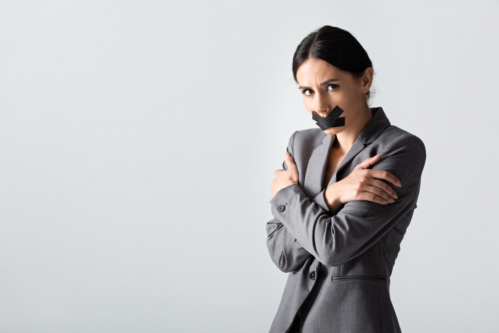 donna d'affari con scotch nastro adesivo sulla bocca in piedi con le braccia incrociate isolato su bianco, concetto di disuguaglianza di genere - Foto, immagini
