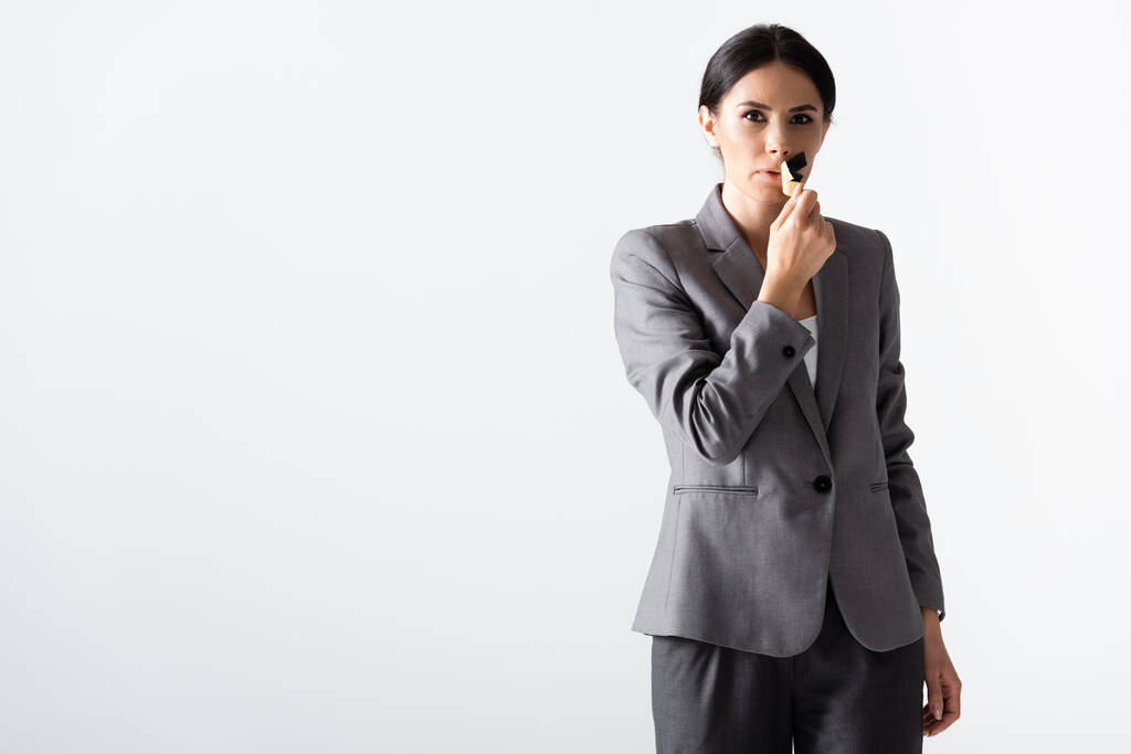 Geschäftsfrau nimmt Klebeband auf Mund isoliert auf weißem, Geschlechterungleichheitskonzept ab  - Foto, Bild