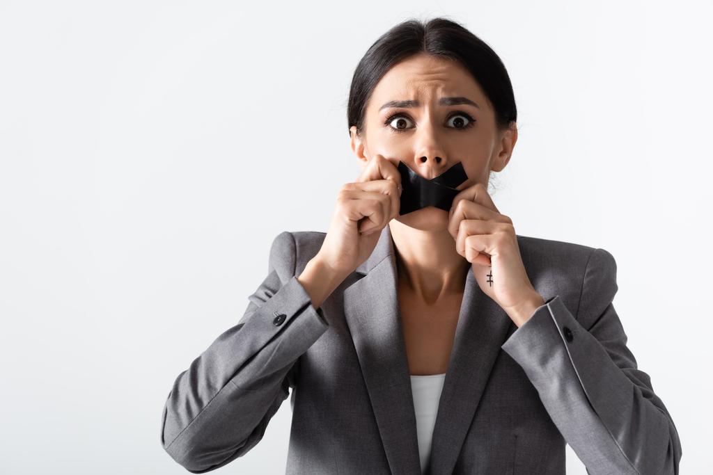 verängstigte Geschäftsfrau berührt Klebeband auf dem Mund isoliert auf weiß, Geschlechterungleichheit Konzept  - Foto, Bild