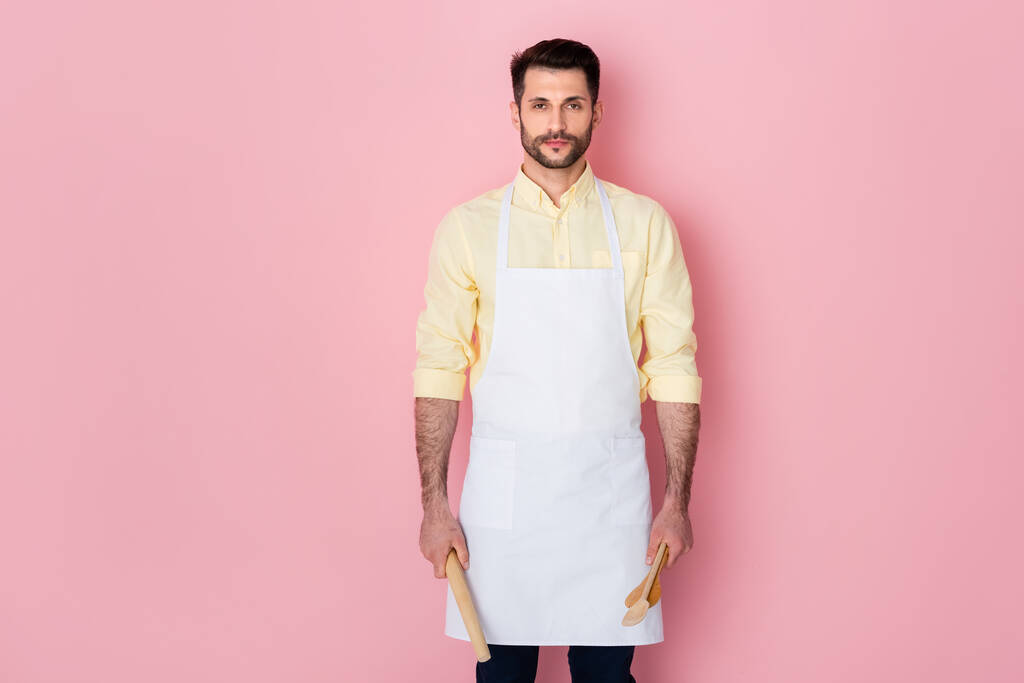 bel homme barbu tenant rouleau à pâtisserie et cuillère en bois sur rose  - Photo, image