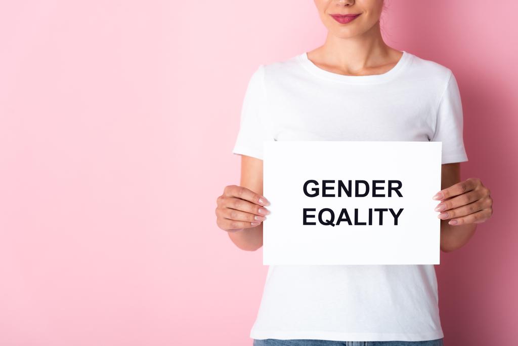 vista ritagliata della donna in t-shirt bianca con cartello con scritte di uguaglianza di genere su rosa  - Foto, immagini