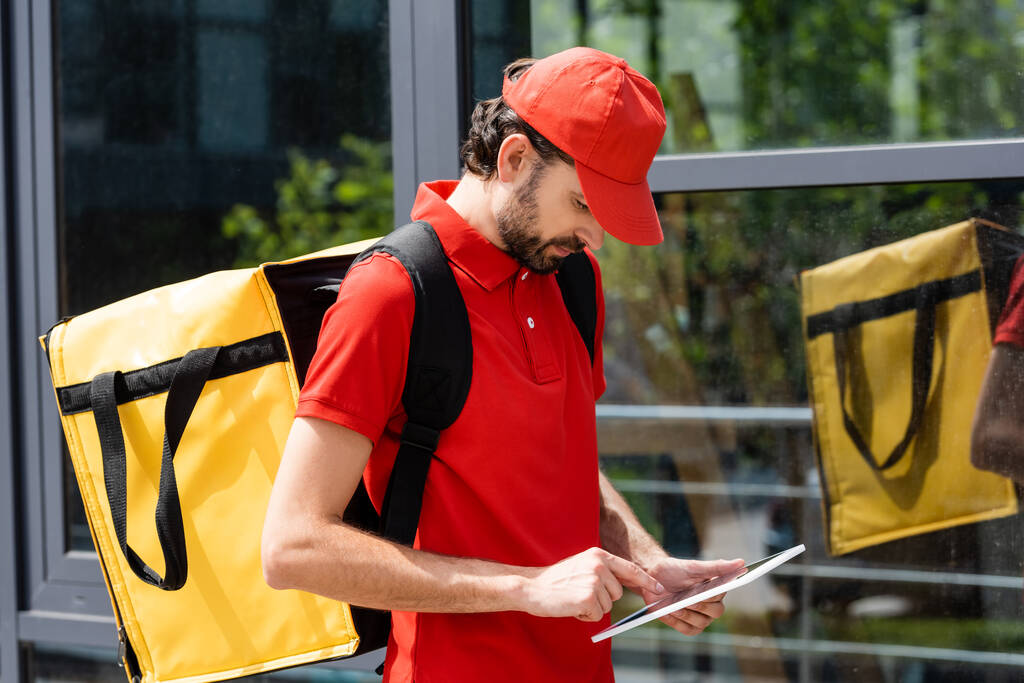 Kurier z plecakiem termo przy użyciu tabletu cyfrowego na ulicy miejskiej  - Zdjęcie, obraz