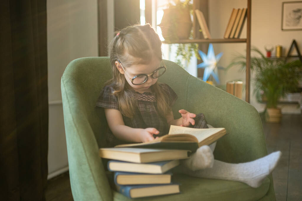 Egy aranyos kislány szemüvegben, aki könyveket olvas. Vissza az iskolába. - Fotó, kép