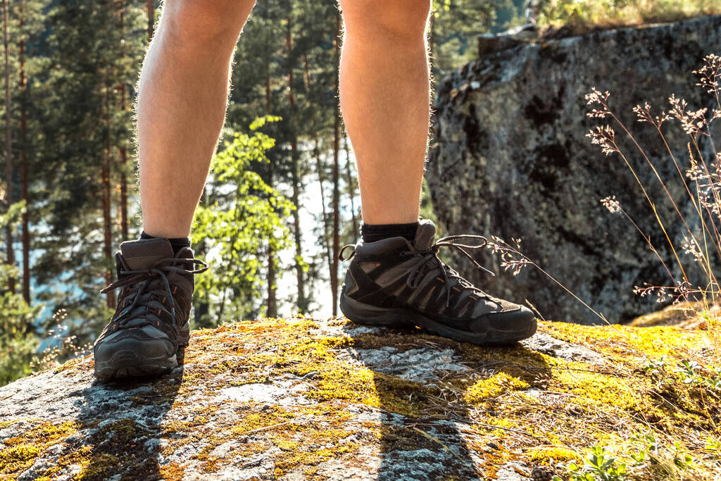 Yürüyüş ayakkabılı bacaklar. İskandinav dağlarında tek başına yürüyüş yapan bir adam. Aktif, sağlıklı yaşam tarzı macerası. Seyahat ve tatil kavramı - Fotoğraf, Görsel