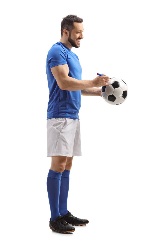 Perfil de comprimento total tiro de um atleta assinando um autógrafo em uma bola de futebol isolada no fundo branco
 - Foto, Imagem
