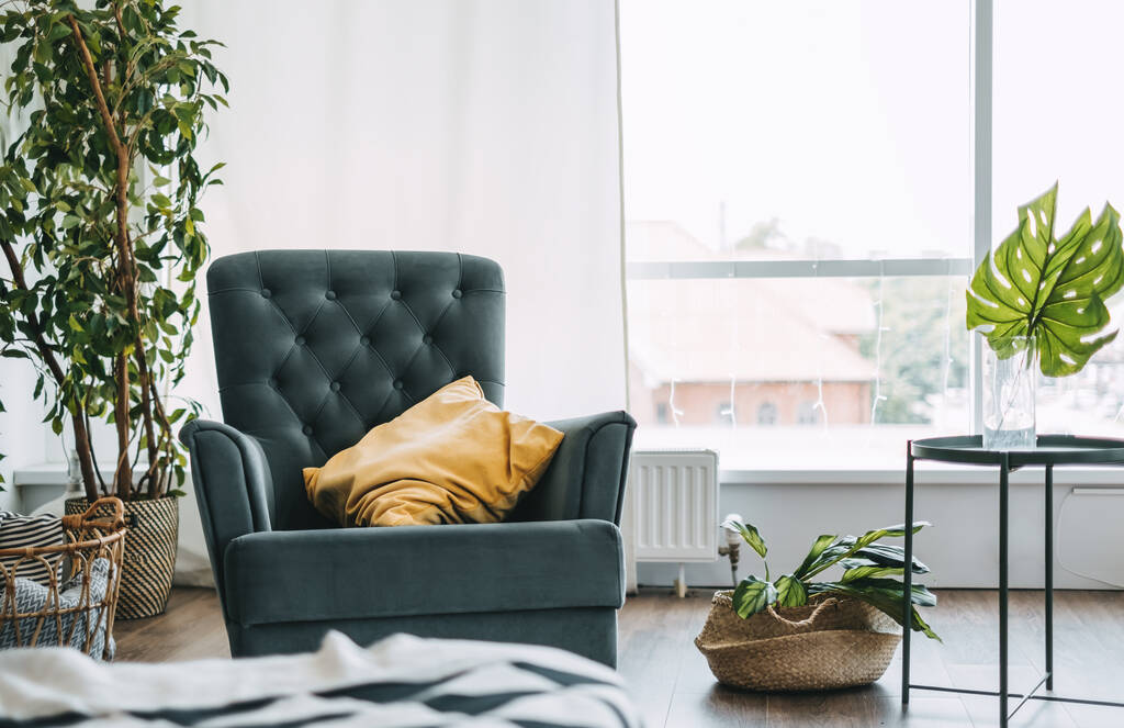 Salon avec plantes vertes et grand fauteuil avec oreiller près de la fenêtre, confort à la maison, détails intérieurs. Photo de haute qualité - Photo, image