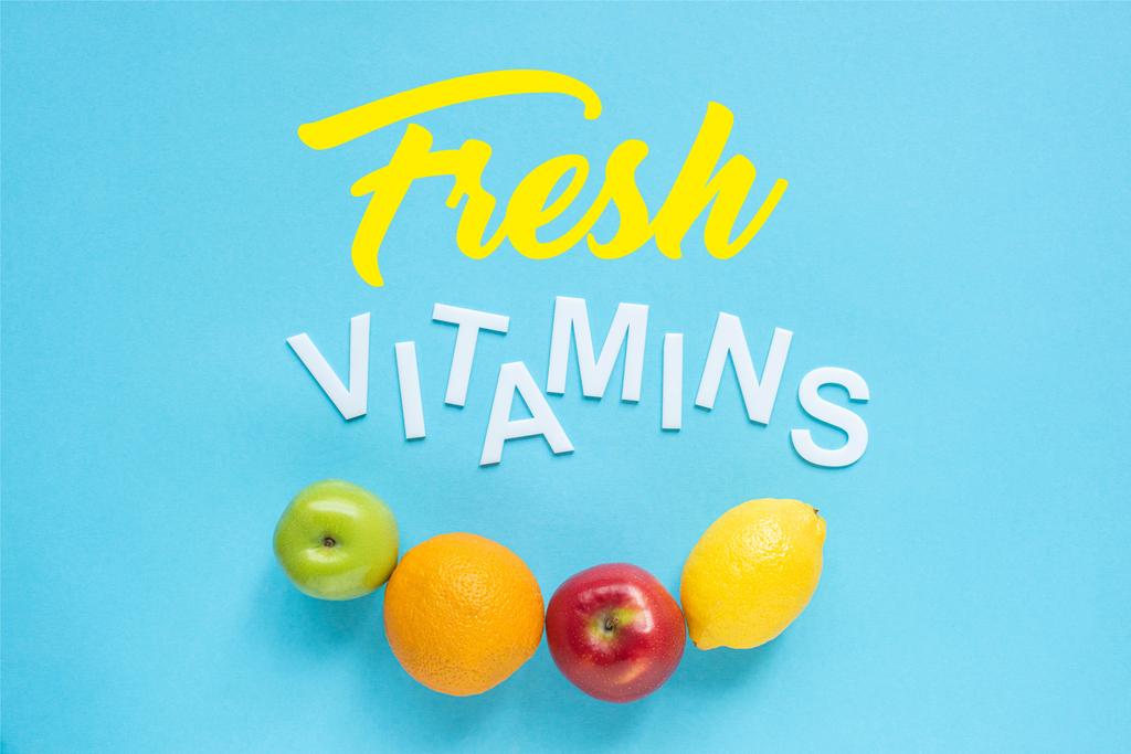 κορυφαία άποψη των ώριμων φρούτων και λέξεις φρέσκες βιταμίνες σε μπλε φόντο - Φωτογραφία, εικόνα