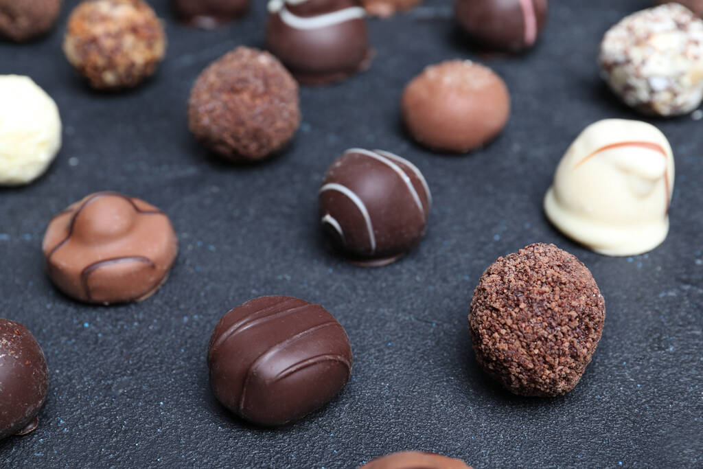 Diferentes dulces de chocolate sabrosos en la mesa negra
 - Foto, Imagen