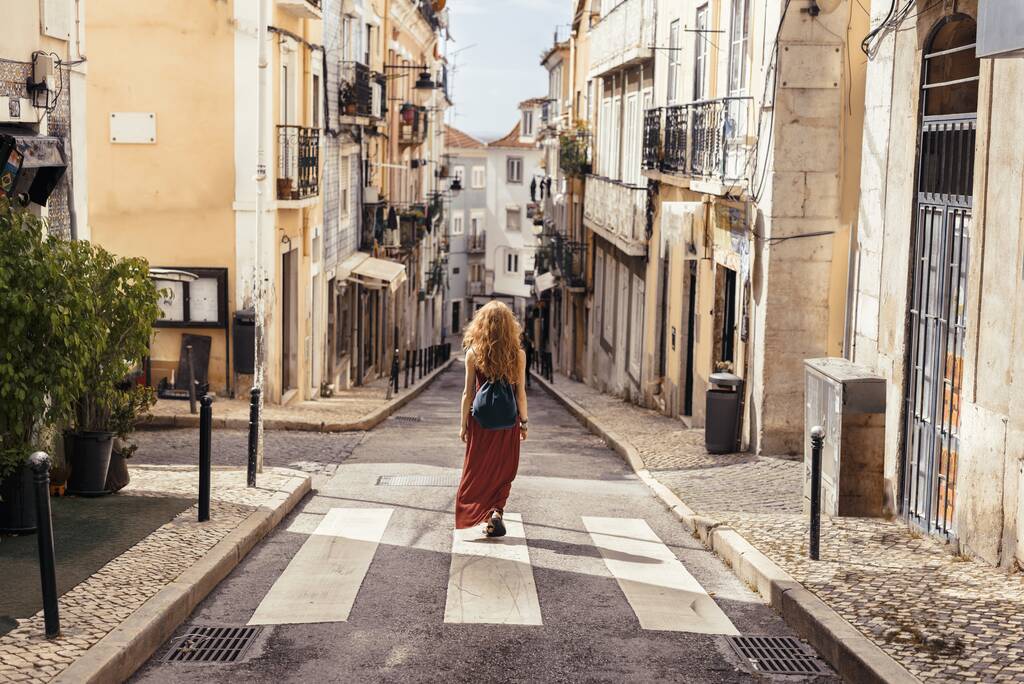 Ένα τοπίο στιγμιότυπο μιας νεαρής γυναίκας ταξιδιώτη απολαμβάνοντας τη θέα στους δρόμους των πορτογαλικών και ισπανικών πόλεων - Φωτογραφία, εικόνα