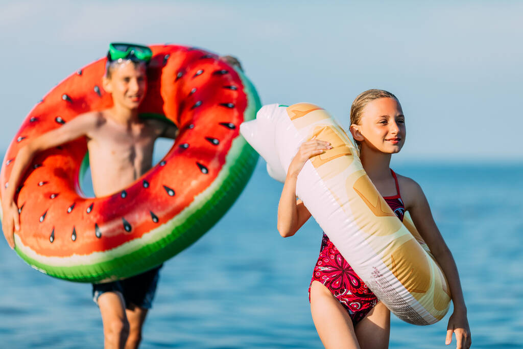 Happy crianças irmão e irmã se divertir na praia com círculos de natação infláveis. férias de verão
 - Foto, Imagem