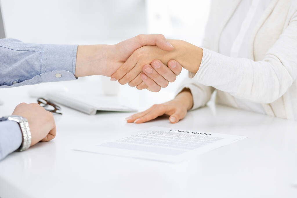Rento pukeutunut liikemies ja nainen kättelee sopimuksen allekirjoittamisen jälkeen valkoinen värillinen toimisto. Kädenpuristuksen käsite - Valokuva, kuva