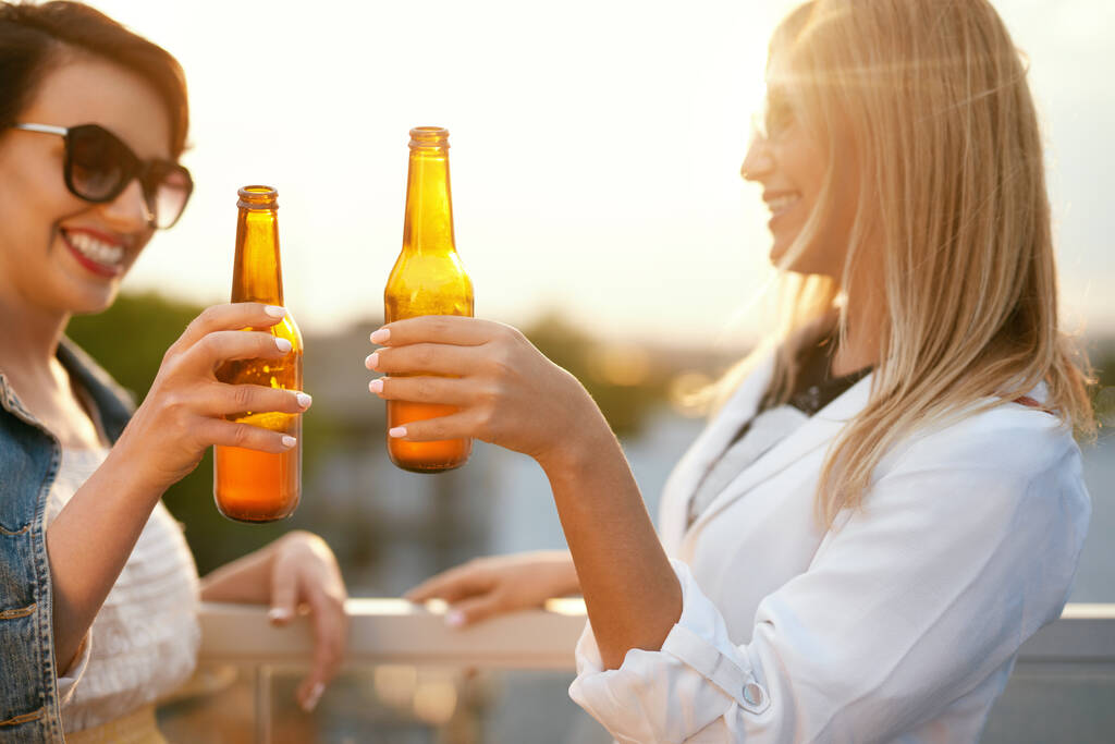 Mulheres bebendo cerveja de garrafas ao ar livre
 - Foto, Imagem
