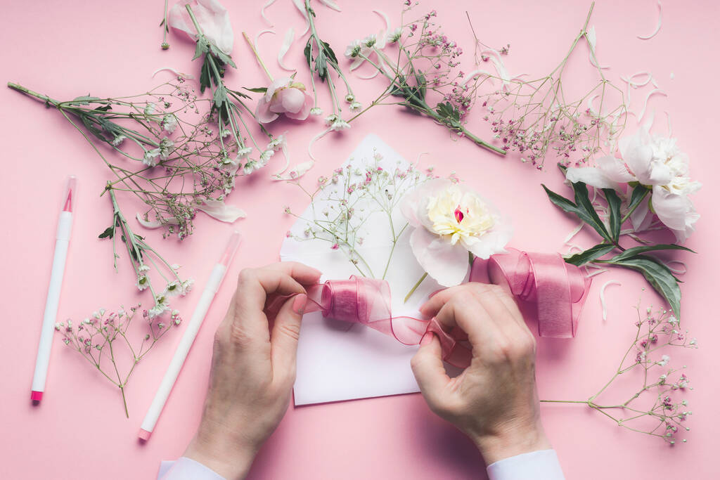Kobieta Ręka robi kartkę z pozdrowieniami z kopertą z kwiatami. Ślub, zaproszenie, Walentynki, koncepcja Dnia Matki. Płaskie ułożenie, widok z góry, przestrzeń do kopiowania - Zdjęcie, obraz