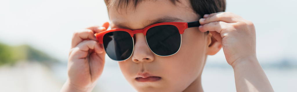Panoramaaufnahme eines niedlichen und ernsthaften Jungen mit stylischer Sonnenbrille  - Foto, Bild
