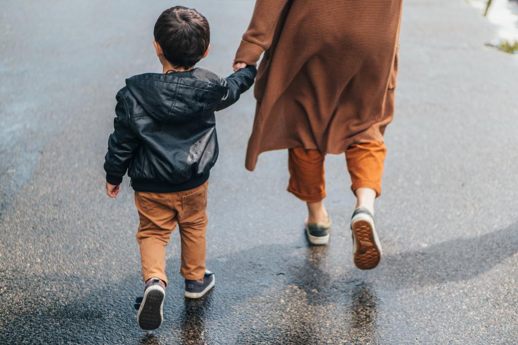 vista recortada de la mujer cogida de la mano y caminando con su hijo
 - Foto, Imagen