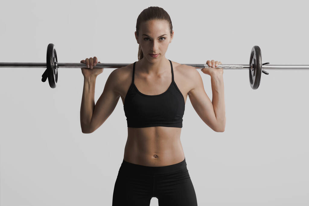 Aufnahme einer schönen jungen Frau im Trainingsgerät beim Heben von Gewichten - Foto, Bild