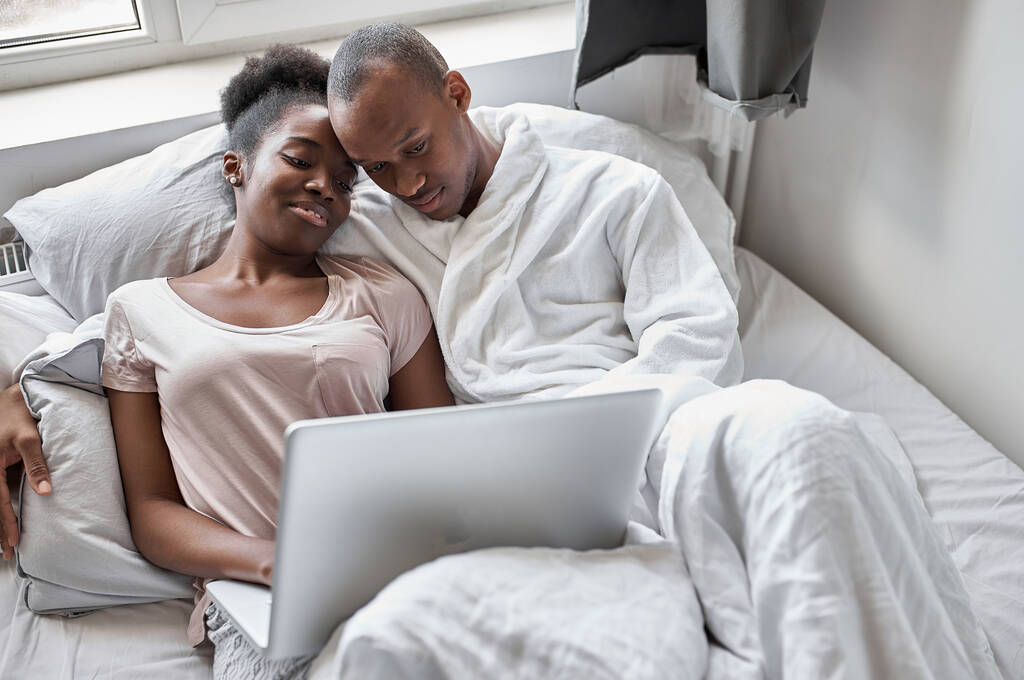 блаженна чорна пара на ліжку дивиться на екран ноутбука
 - Фото, зображення