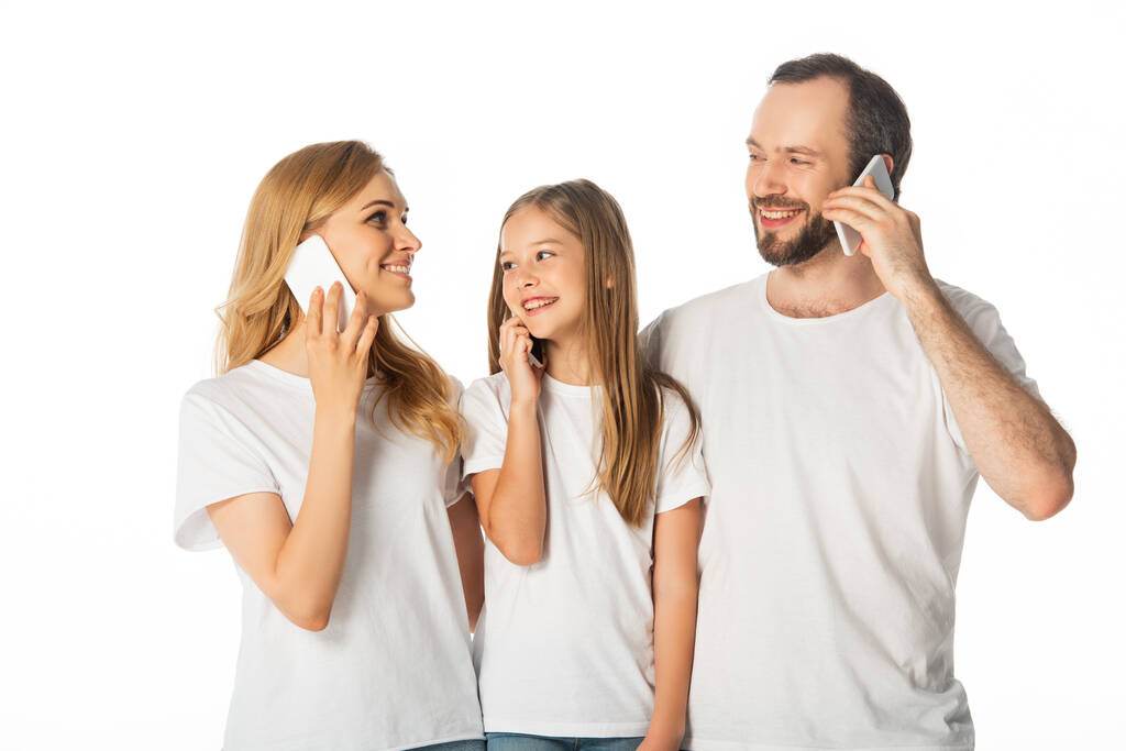 famille souriante en t-shirts blancs parlant sur les smartphones isolés sur blanc - Photo, image