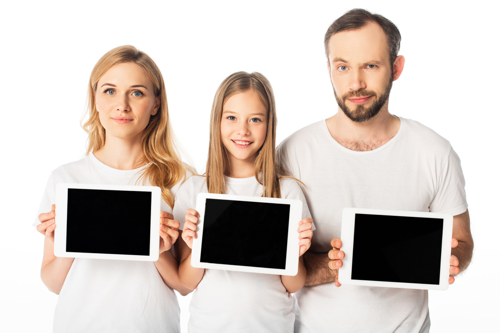 усміхнена сім'я в білих футболках тримає цифрові планшети ізольовані на білому
 - Фото, зображення