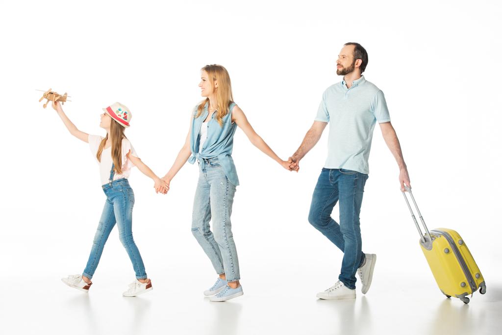 heureux famille tenant la main tout en marchant avec sac de voyage isolé sur blanc - Photo, image