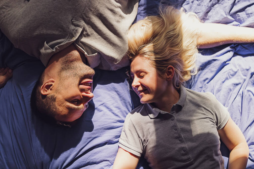 Hiteles felvétel fiatal pár feküdt az ágyon kora reggel egy napsütéses napon. - Fotó, kép