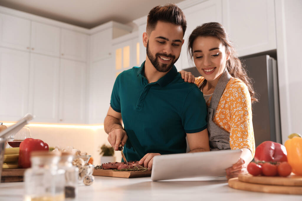Υπέροχο νεαρό ζευγάρι με tablet μαγείρεμα μαζί στην κουζίνα - Φωτογραφία, εικόνα